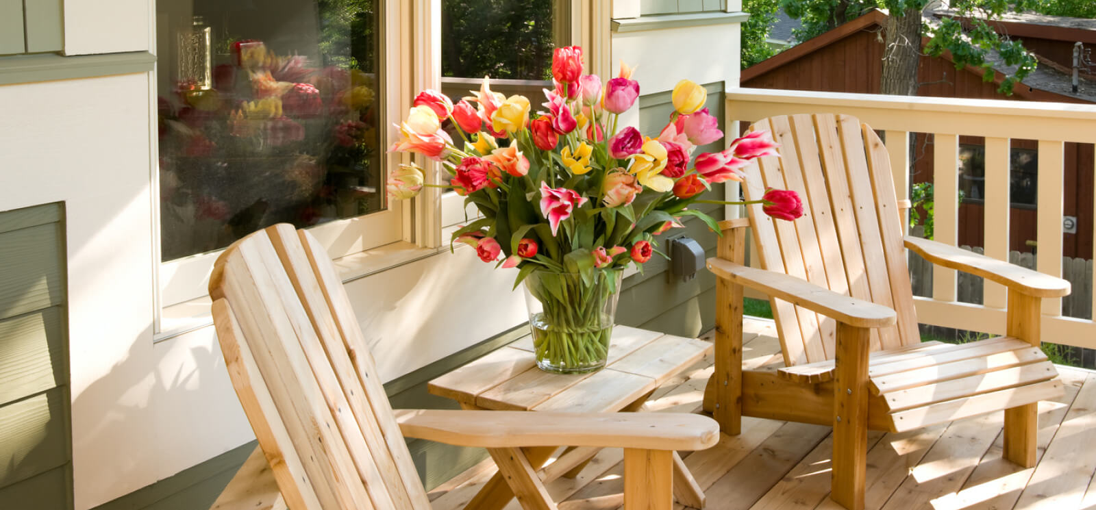 Wooden chairs on a patio with a vase of flowers