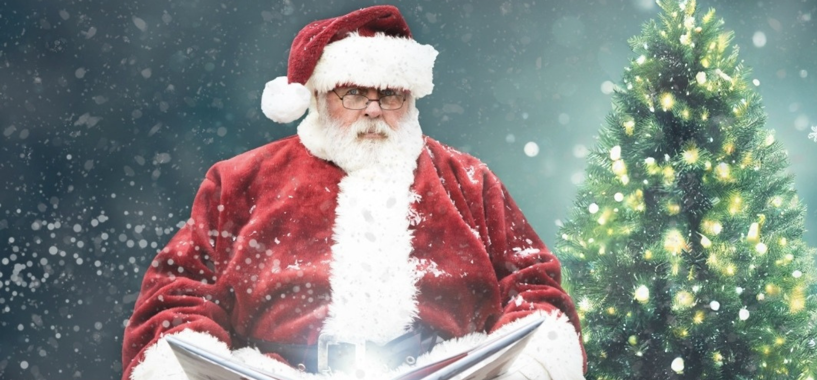 Santa reading a book. Christmas tree in the background. 