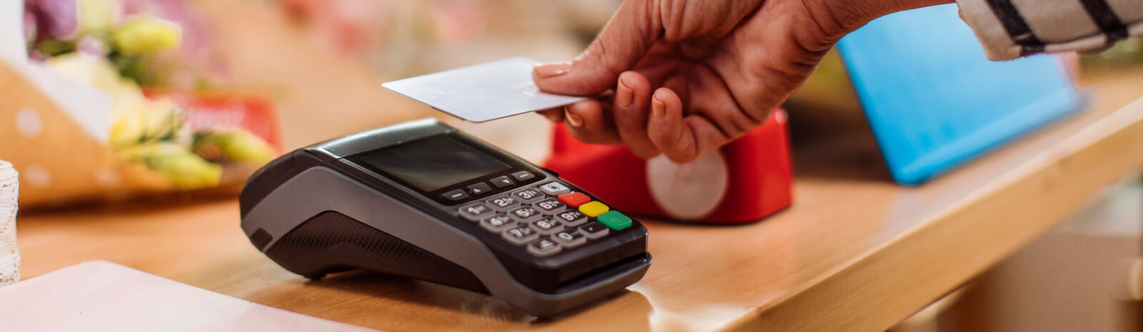 Close up of a hand holding a credit card against a card reader