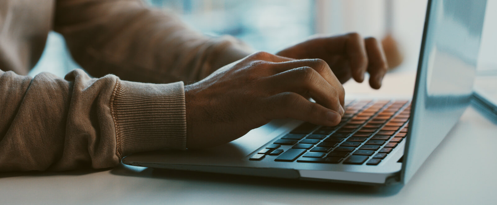 Close up of hands using a laptop keyboard