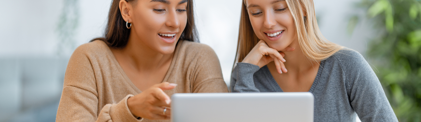 two women talking in front of a laptop